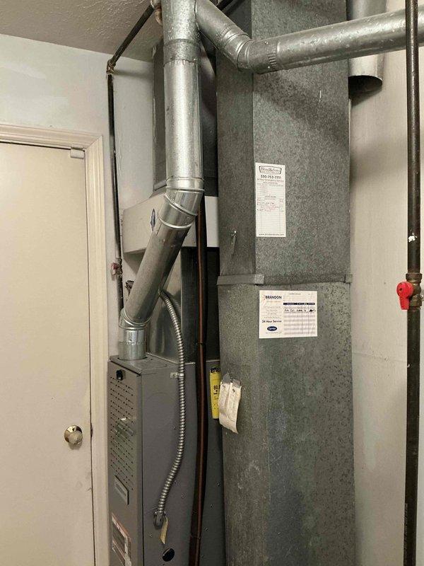 Conducted comprehensive on-site evaluation for complete HVAC system replacement including existing furnace, air conditioning system, and water heating equipment. Assessed current dark-colored furnace unit with associated metallic ductwork configuration, gray air handler/filter cabinet, and white cylindrical water heater with top-mounted venting system. Documented existing equipment specifications, installation conditions, and mechanical room layout to provide accurate replacement options for furnace, AC unit, and choice between traditional tank or tankless water heater configurations.