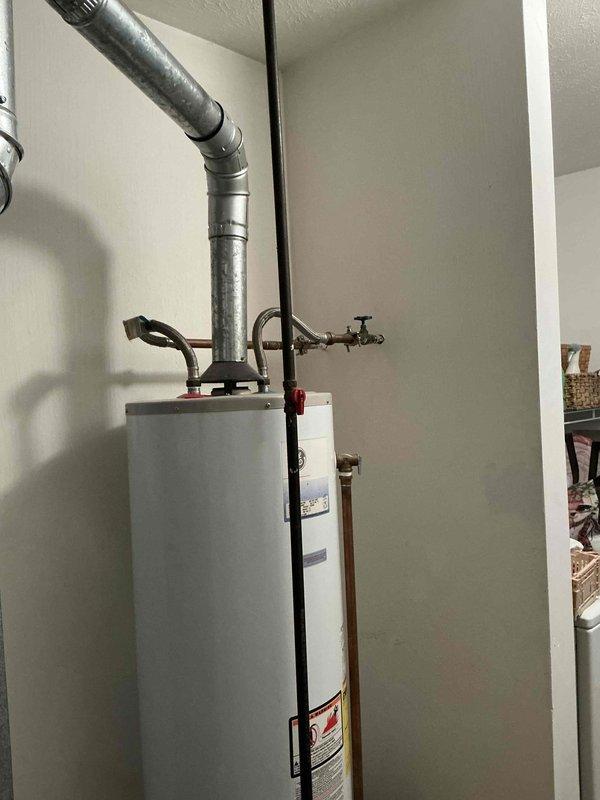 Conducted comprehensive on-site evaluation for complete HVAC system replacement including existing furnace, air conditioning system, and water heating equipment. Assessed current dark-colored furnace unit with associated metallic ductwork configuration, gray air handler/filter cabinet, and white cylindrical water heater with top-mounted venting system. Documented existing equipment specifications, installation conditions, and mechanical room layout to provide accurate replacement options for furnace, AC unit, and choice between traditional tank or tankless water heater configurations.