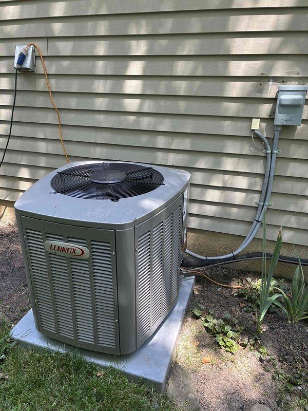 Completed MVP recurring cooling maintenance visit on residential Lennox outdoor condensing unit. Performed visual inspection of equipment exterior, verified proper placement on condensate pad, and inspected refrigerant line connections. Accessed internal components to examine condenser coil condition, noting dust and dirt accumulation on heat exchanger fins requiring attention during routine maintenance procedures.