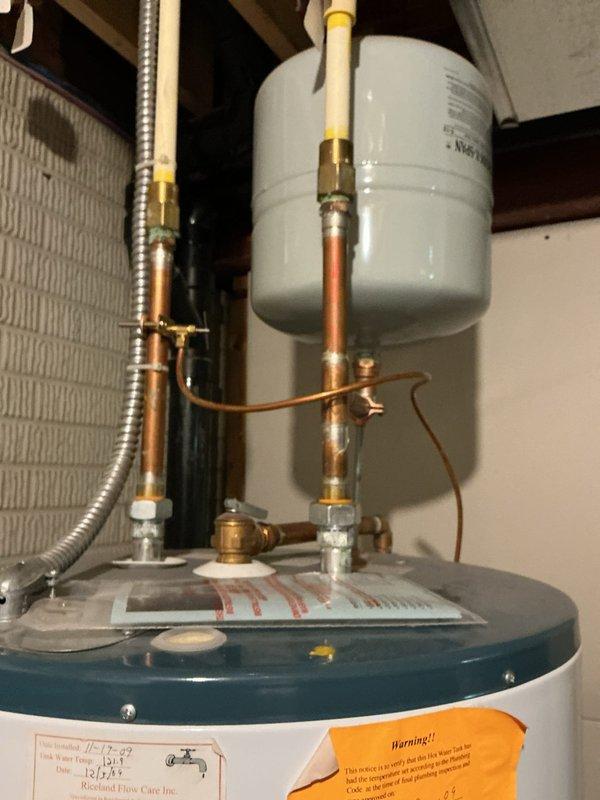 Performed flush and fill service on 17-year-old natural gas tanked water heater per promotional coupon request. Identified and replaced leaking copper pipe section during inspection. Water heater system includes properly installed expansion tank, copper supply lines with brass fittings, yellow gas line, and appropriate safety valves. All connections tested for leaks and system returned to normal operation.