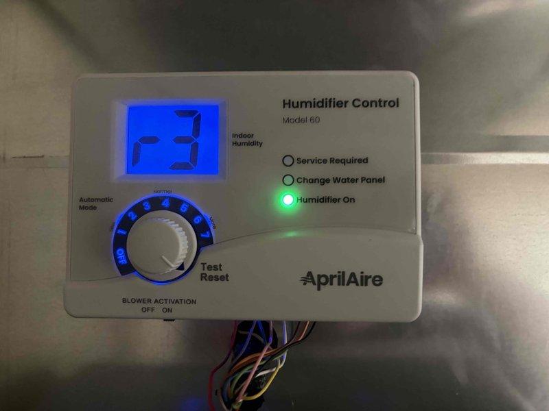 Completed installation of a complete HVAC system including a 90% efficiency furnace, air conditioning unit, and whole-home humidification system. Installed AprilAire Model 60 humidifier control panel with digital display and automatic mode functionality, properly wired and mounted to the furnace cabinet. The control panel is operational with the humidifier indicator illuminated, confirming successful system integration. Installed outdoor condensing unit on a protective pad with crushed stone base, positioned adjacent to the building exterior with proper clearances maintained. Connected electrical disconnect box to the outdoor unit and completed all refrigerant line connections. Verified all system components are communicating correctly, humidifier control is responding to indoor humidity levels, and the complete system is operational and ready for use.