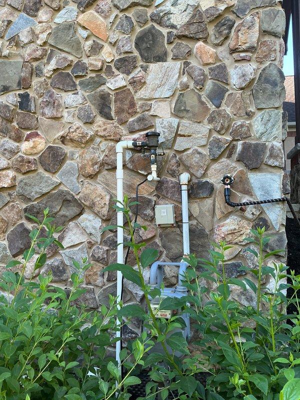 Completed annual backflow prevention device testing on exterior-mounted RPZ assembly. Performed standard five-point test procedure to verify proper operation of check valves, relief valve, and differential pressure across the assembly. Unit CB07435 tested within acceptable parameters and maintained required air gap protection. Documented device condition with photographic evidence showing proper mounting configuration on stone exterior wall with white PVC piping connections. All components functioning correctly with no leaks or deficiencies observed.