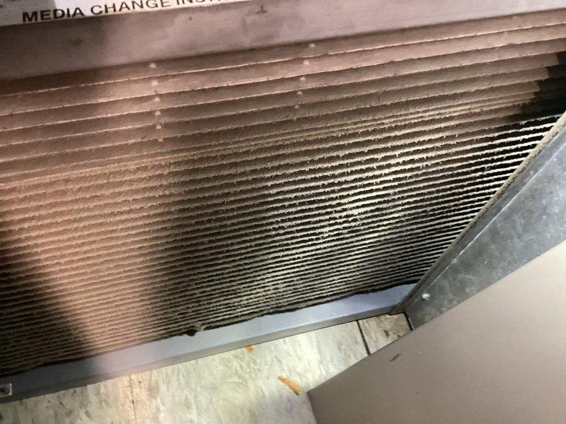 Completed MVP cooling maintenance visit. Inspected evaporator coil and found significant accumulation of dust and debris between fins, particularly in center and right sections, indicating extended operation without recent cleaning. Documented condition of heat exchanger with visible discoloration and particle buildup affecting airflow efficiency. Inspected inline filter housing and associated PVC piping connections in mechanical area, verifying proper installation and system integrity. All components photographed for maintenance records.