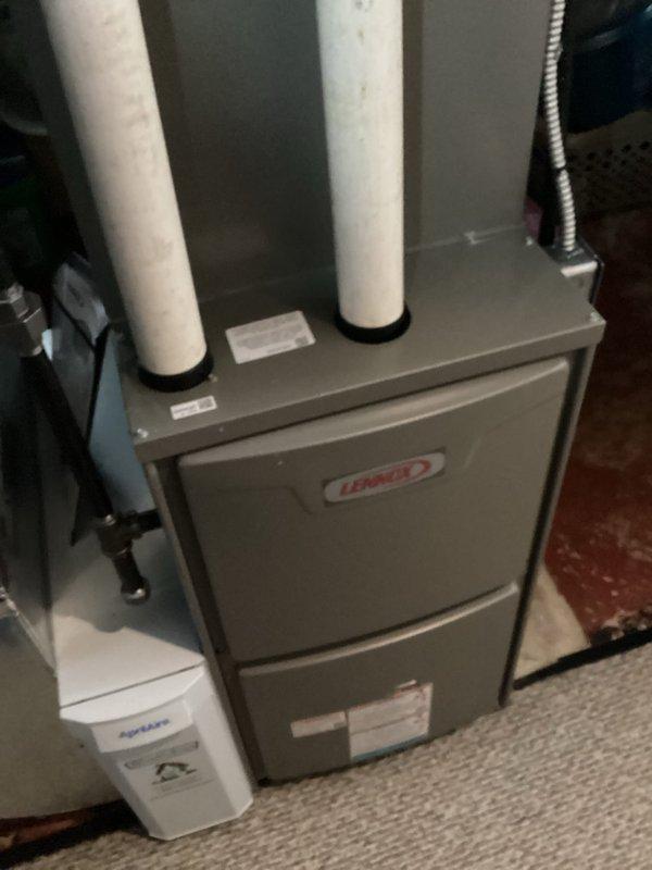 Responded to service call for persistent condensate leak on newly installed Lennox furnace. Upon inspection, discovered leak at different location than previous repair attempt. Examined PVC condensate drain assembly and trap connections. Documented existing conditions with photos showing furnace installation, condensate drain piping configuration, and PVC trap assembly with metal pipe connections. Identified source of new leak and addressed drainage issue to prevent further water discharge from unit.