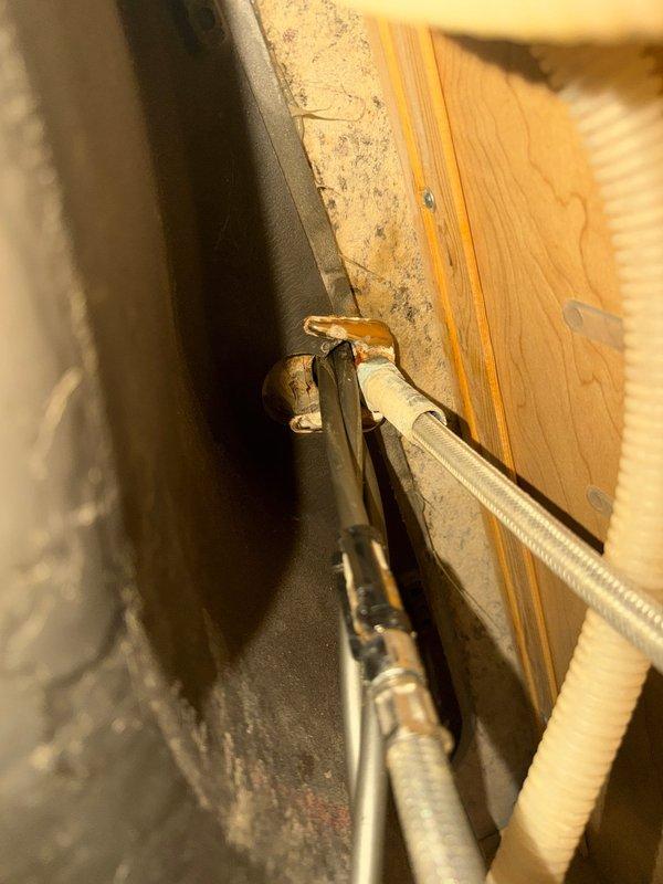 Responded to service call for water leak beneath kitchen sink. Upon arrival, performed diagnostic inspection of plumbing connections and supply lines under sink cabinet. Inspected shut-off valves, P-trap assembly, and all visible water supply connections for signs of active leaking or moisture damage. Examined the installation area including adjacent mechanical systems and structural components in the confined space below the sink. Verified proper operation of kitchen faucet with high-arc spout and side spray attachment. Documented existing conditions with photographs showing plumbing infrastructure, supply lines, and sink fixture installation. Identified source of reported leak and assessed surrounding areas for water damage or compromised connections.