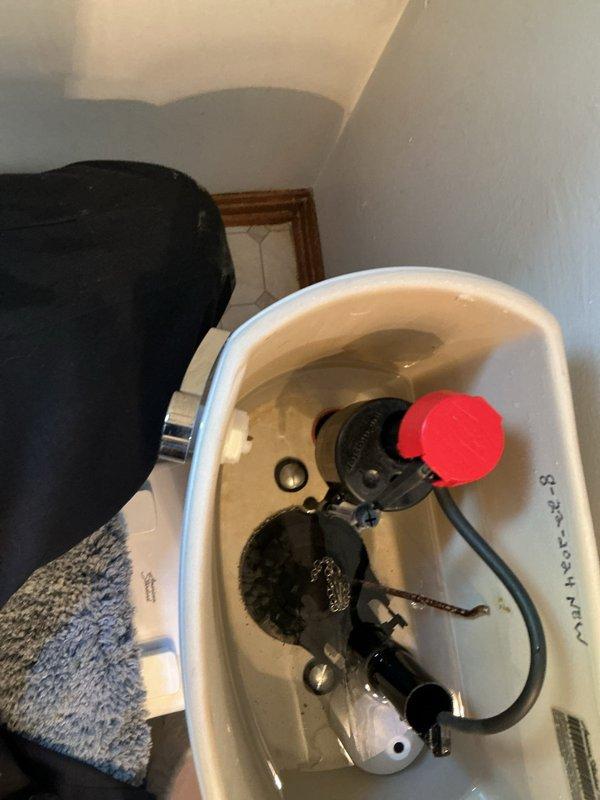 Responded to service call for broken American Standard toilet handle that had detached from front-mounted tank position. Removed damaged handle assembly and associated hardware, including corroded copper linkage arm and worn mounting components. Installed replacement toilet handle with new mounting hardware, lever arm, and connecting chain to restore proper flush functionality.