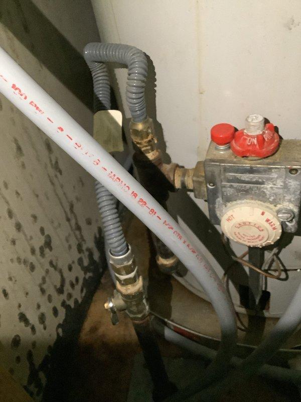 Responded to service call for active water leak originating from top of tanked water heater in 1978 manufactured home. Upon arrival, inspected unit and confirmed leak at top connections with visible water damage and staining on surrounding walls indicating prolonged moisture exposure. Assessed gas control valve, flexible gas connectors with brass fittings, and PVC venting system for proper operation and code compliance. Evaluated copper supply lines showing oxidation and previous repair attempts with tape wrapping. Determined extent of corrosion on piping and water heater components. Documented condition of installation including deteriorated wall surfaces with water staining and spotting consistent with chronic leak issues. Provided assessment and recommendations for repair versus replacement options given age of home and existing plumbing infrastructure.