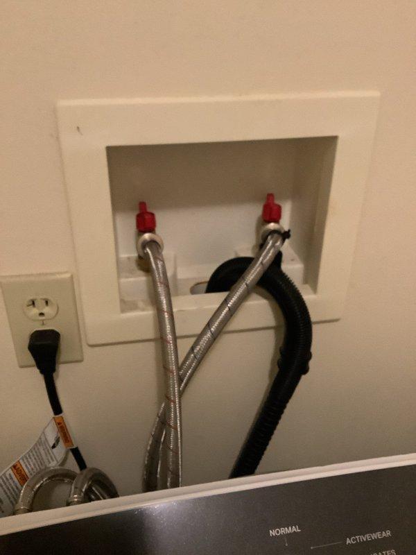 Responded to service call for non-functioning hot water supply to washing machine. Upon inspection, found the hot water shut-off valve (red handle) in the wall-mounted connection box was faulty and preventing water flow to the appliance. Replaced defective hot water valve, verified proper connection to braided stainless steel supply line, tested system operation, and confirmed hot water now flowing correctly to washing machine while cold water line remained functional throughout service.