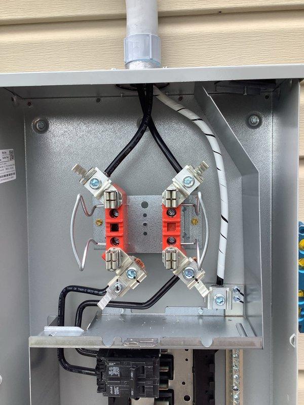 Completed 100-amp service upgrade with relocation of electrical service panel to deck area to ensure proper 3-foot clearance from windows and comply with 2023 National Electrical Code requirements. Installed new exterior disconnect enclosure with dual meter sockets, main circuit breakers, and copper bus bar assembly. Updated grounding system with proper bonding conductors and ground wire connections. Relocated service entry point upward to maintain required clearances from riser and hot taps relative to window openings. Installed gray PVC conduit for weatherproof cable routing along exterior wall. All electrical connections properly terminated with appropriate torque specifications, and all components securely mounted to building structure with proper fasteners and weatherproof fittings.