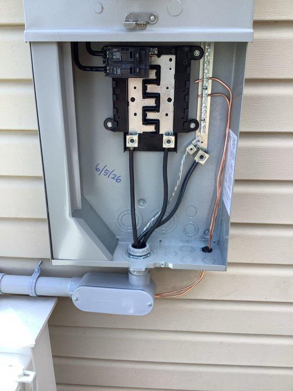 Completed 100-amp service upgrade with relocation of electrical service panel to deck area to ensure proper 3-foot clearance from windows and comply with 2023 National Electrical Code requirements. Installed new exterior disconnect enclosure with dual meter sockets, main circuit breakers, and copper bus bar assembly. Updated grounding system with proper bonding conductors and ground wire connections. Relocated service entry point upward to maintain required clearances from riser and hot taps relative to window openings. Installed gray PVC conduit for weatherproof cable routing along exterior wall. All electrical connections properly terminated with appropriate torque specifications, and all components securely mounted to building structure with proper fasteners and weatherproof fittings.