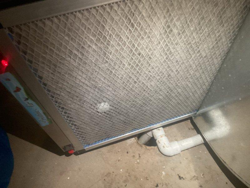 Completed MVP Cooling Visit maintenance inspection of residential HVAC system. Inspected air filter assembly with diamond-pattern mesh grill, verified proper installation and fitment within the air handler unit, and documented system components including blower motor housing, ductwork, and condensate drain piping. All equipment found operating within normal parameters with filter in serviceable condition.