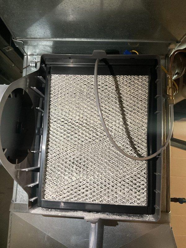 Completed MVP Cooling Visit maintenance inspection of residential HVAC system. Inspected air filter assembly with diamond-pattern mesh grill, verified proper installation and fitment within the air handler unit, and documented system components including blower motor housing, ductwork, and condensate drain piping. All equipment found operating within normal parameters with filter in serviceable condition.