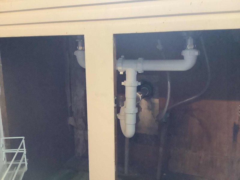 Replaced kitchen faucet with new single-handle unit including side spray assembly. Installed two new basket strainers in double-basin stainless steel sink. Replaced center outlet waste assembly, P-traps, and associated drain piping under both sink compartments with new PVC components to ensure proper drainage and code compliance.