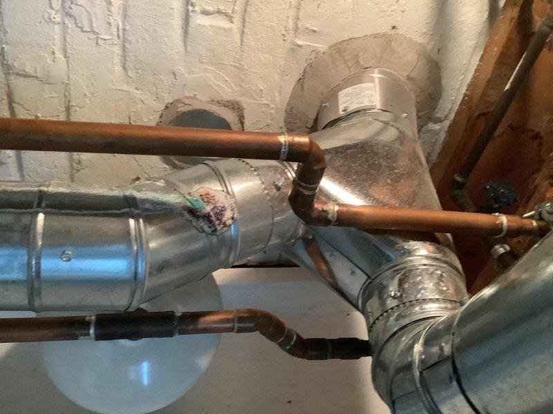 Responded to a recurring water leak from a fitting located directly above the hot water tank. Upon inspection, identified a leaking copper pipe connection at a soldered joint that was causing water to drip onto the top of the water heater. Repaired the defective fitting by re-soldering the connection to ensure a proper watertight seal. Verified all surrounding copper piping and connections in the mechanical space for additional leaks or potential issues. Tested the repaired fitting under pressure to confirm the leak was resolved and no further dripping occurred.