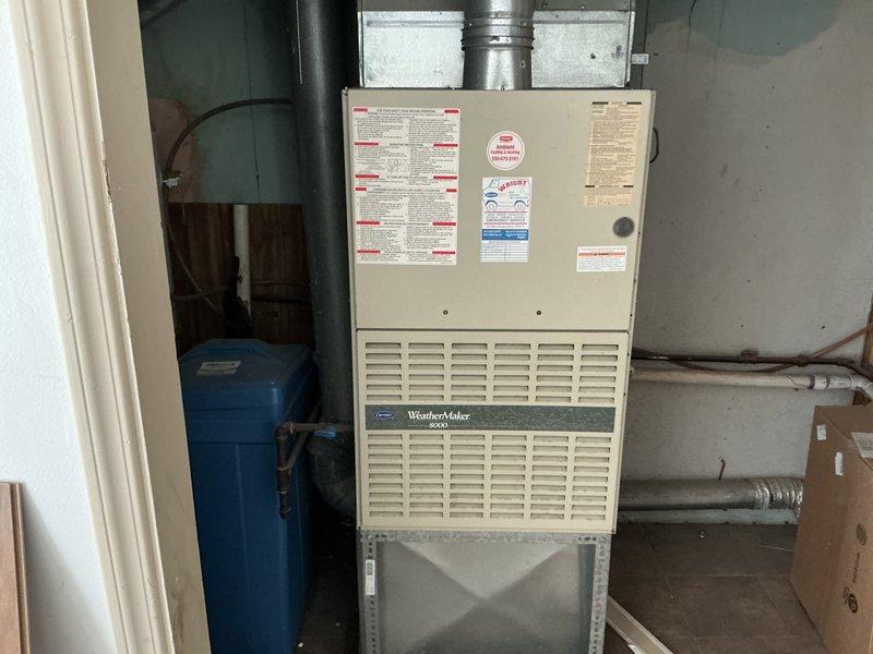Conducted comprehensive on-site evaluation for complete HVAC system replacement of existing WeatherMaker 8000 furnace and air conditioning unit in residential basement mechanical room. Documented current equipment configuration including ductwork connections, electrical requirements, and clearance specifications, photographed existing installation showing furnace with horizontal ventilation slats, metallic supply ductwork, and adjacent blue pressure tank with associated piping. Provided detailed replacement estimate covering removal of existing equipment and installation of new high-efficiency heating and cooling system with proper sizing calculations based on home requirements.