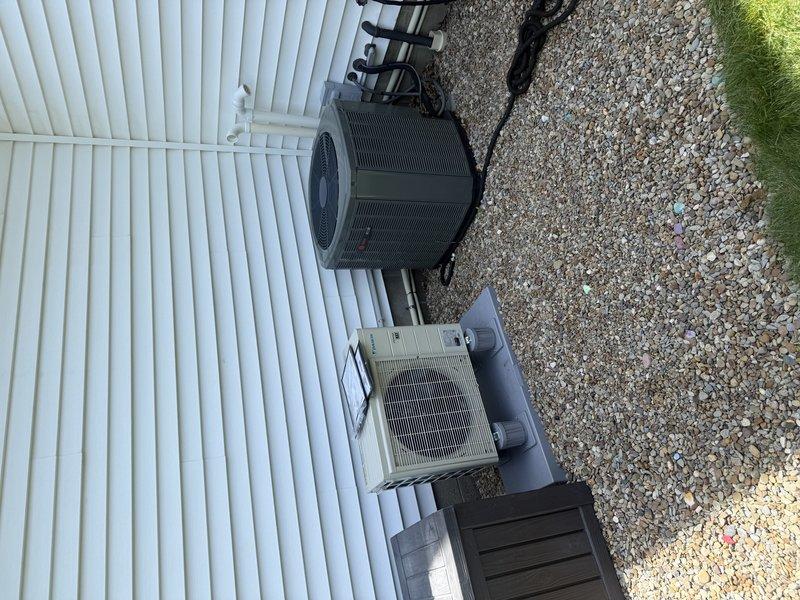 Completed installation of 1-to-1 mini split system including outdoor condensing unit mounted on exterior wall with proper refrigerant line routing and electrical connections. Installed 15-amp Edison fuses on dedicated disconnect for equipment protection. System positioned on gravel pad with secure mounting and proper clearances maintained for optimal airflow and serviceability.