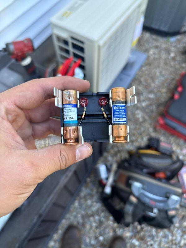 Completed installation of 1-to-1 mini split system including outdoor condensing unit mounted on exterior wall with proper refrigerant line routing and electrical connections. Installed 15-amp Edison fuses on dedicated disconnect for equipment protection. System positioned on gravel pad with secure mounting and proper clearances maintained for optimal airflow and serviceability.