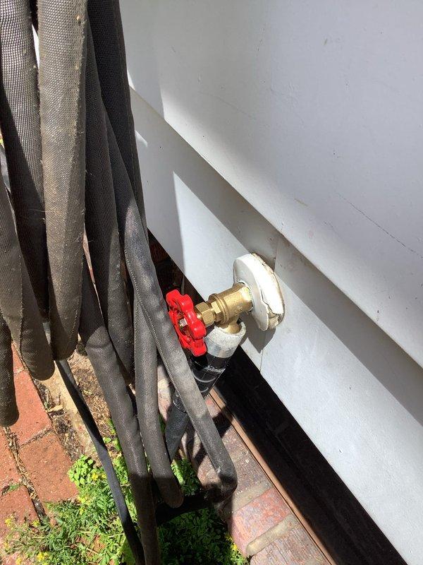 Replaced heavily leaking outdoor faucet on century-old home with new frost-free sillcock assembly, including shutoff valve installation in basement crawl space. Work involved accessing existing copper supply lines through cobweb-filled basement area, installing new brass valve with protective cap and red wheel handle through exterior wall, and pressure testing system to ensure leak-free operation and proper drainage to protect home's exterior from further water damage.