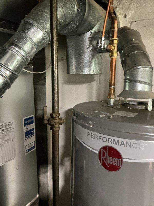Conducted on-site assessment of a 9-year-old Rheem Performance tanked water heater exhibiting active leakage. Inspected the unit and surrounding plumbing connections, including copper supply lines, brass shut-off valves, pressure relief valve, and associated galvanized ductwork. Documented existing installation configuration with photographs showing tank condition, pipe routing, and mechanical room layout. Provided estimate for complete water heater replacement due to tank failure, as the existing unit had reached the end of its serviceable life and repair was not economically viable.