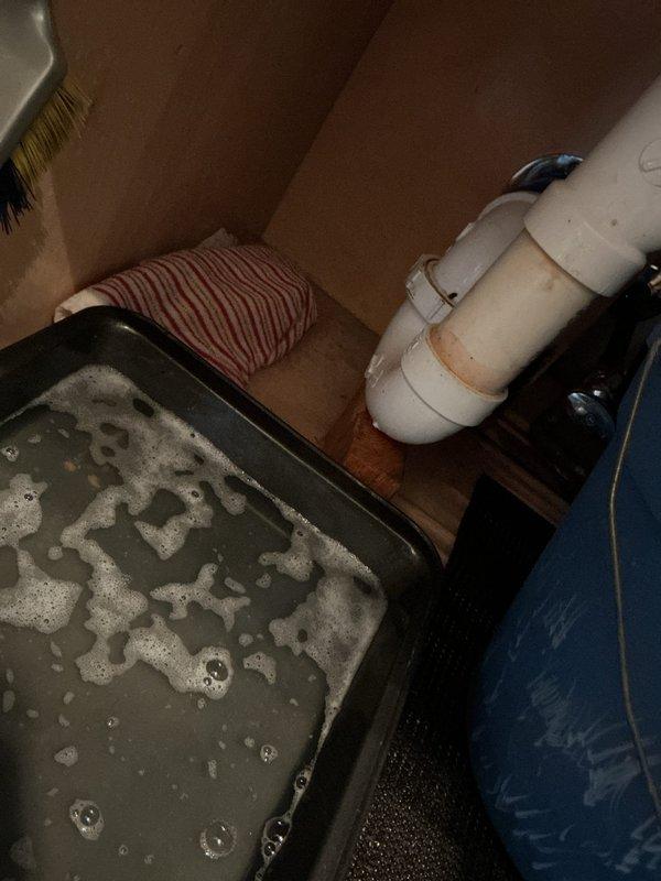 Responded to kitchen drain clog in 28-year-old residence. Upon inspection, located clogged drain line in basement utility area beneath kitchen sink. Identified blockage in PVC trap assembly causing drainage backup and standing water accumulation in drip pan. Cleared obstruction from drain system, flushed lines to restore proper flow, and verified drainage functionality. System tested and operating normally upon completion.