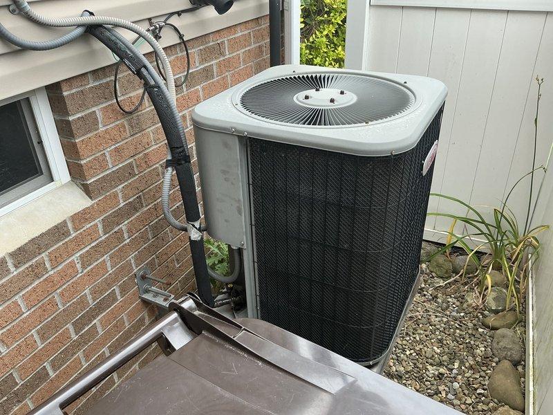 Provided estimate for replacement of 19-year-old residential air conditioning system. Existing outdoor condenser unit currently positioned on concrete pad against brick exterior with refrigerant lines running along building wall. Quoted complete system replacement including new condenser unit, installation, and necessary line work.