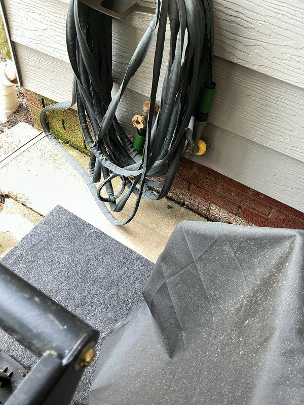 Responded to service call for outdoor spigot leaking into building siding. Upon inspection, identified water intrusion at the exterior faucet connection point where moisture was migrating upward behind the siding material. Assessed the hose bib mounting area and surrounding foundation for damage, documented conditions showing evidence of water exposure on concrete foundation and soil saturation near the fixture. Completed diagnostic evaluation and photographic documentation of the affected areas including the spigot installation point and adjacent building exterior.