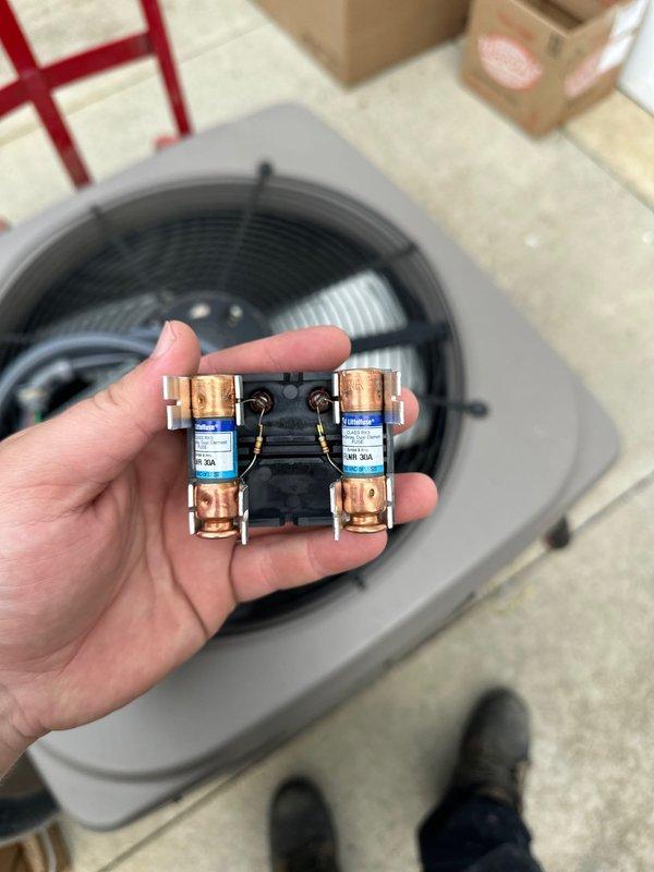 Completed installation of new Lennox air conditioning condensing unit with matching evaporator coil. Unit was properly positioned on elevated platform stand against exterior wall with adequate clearance for airflow and service access. Electrical connections were established including installation of new fuses and disconnect components to meet code requirements. System was tested for proper operation including fan motor function and electrical continuity. Unit installation includes professional landscaping consideration with existing ferns maintained around equipment location.
