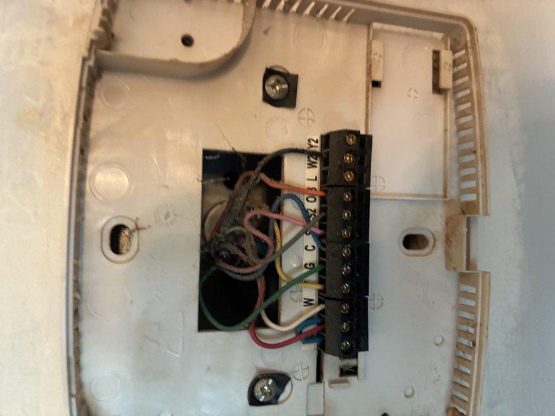 Responded to service call for non-functional thermostat. Upon inspection, found existing thermostat with failed internal components despite battery replacement attempt. Removed old thermostat wall plate, inspected existing low-voltage wiring connections at terminal block, and verified proper wire routing from air handler. Checked blower motor assembly and electrical connections to ensure system readiness for thermostat replacement.