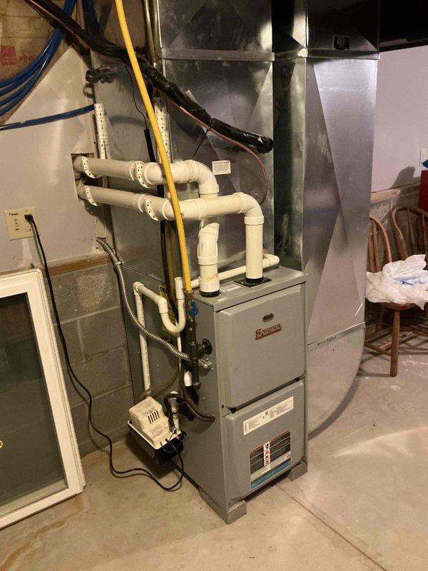 Completed HVAC system replacement estimate for a 12-year-old residential heating and cooling system. Assessed existing Thermolec furnace unit in basement mechanical room with associated ductwork, gas line, condensate drainage, and electrical connections, along with outdoor cylindrical air conditioning unit mounted on concrete pad. Documented current equipment condition, specifications, and installation configuration to provide comprehensive replacement quote for complete system upgrade.