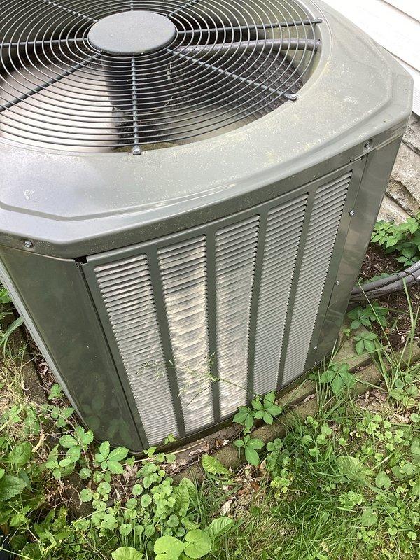 # HVAC Service Completed

Responded to no cooling complaint on 13-year-old residential air conditioning system. Customer reported lukewarm air discharge with suspected refrigerant loss. Upon arrival, performed visual inspection of outdoor condensing unit, which showed significant weathering, dirt accumulation, and algae growth consistent with age and lack of maintenance. Unit exhibited poor external condition with debris around base and vegetation growth affecting clearance.

Inspected indoor air handling components and found heavily soiled air filter with substantial dust and debris accumulation, significantly restricting airflow through the system. Dirty filter was primary cause of reduced cooling performance and lukewarm air complaints. Replaced air filter with new pleated filter to restore proper airflow and system efficiency.

Conducted operational testing following filter replacement. System now operating within normal parameters with improved air delivery and cooling performance