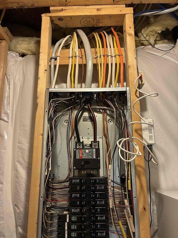 Responded to service call for kitchen circuit issue affecting microwave and refrigerator in 16-year-old residence. Upon arrival, inspected main electrical panel located in basement utility area. Panel showed proper cable organization with bundled conductors entering through wooden framework at top. Tested and inspected dual-column breaker arrangement including main disconnect switch and individual branch circuit breakers. Identified tripped breaker serving kitchen appliance circuit. Reset affected breaker and verified proper operation of both microwave and refrigerator. Confirmed all connections were secure, panel components showed no signs of overheating or damage, and breaker labels were legible. Tested voltage at panel and verified proper function of reset circuit under load. All electrical components functioning normally upon completion. Documented panel condition with photos showing organized wire management and maintained breaker configuration.
