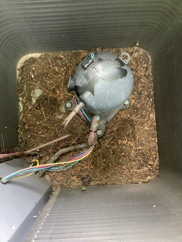 Responded to service call for 9-year-old AC unit making loud banging/rattling noise. Upon inspection, found condenser fan motor heavily contaminated with organic debris including dried grass clippings, leaves, twigs, and plant material that had accumulated through the top grille and around the motor assembly. Debris buildup was causing fan blade obstruction and creating the reported noise. Removed contaminated fan motor from unit, cleared all organic material from condenser cabinet and fan assembly, and cleaned top grille of accumulated debris. Inspected motor bearings and mounting hardware for damage caused by debris interference. Unit restored to proper operation with noise eliminated.