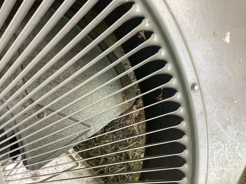 Responded to service call for 9-year-old AC unit making loud banging/rattling noise. Upon inspection, found condenser fan motor heavily contaminated with organic debris including dried grass clippings, leaves, twigs, and plant material that had accumulated through the top grille and around the motor assembly. Debris buildup was causing fan blade obstruction and creating the reported noise. Removed contaminated fan motor from unit, cleared all organic material from condenser cabinet and fan assembly, and cleaned top grille of accumulated debris. Inspected motor bearings and mounting hardware for damage caused by debris interference. Unit restored to proper operation with noise eliminated.