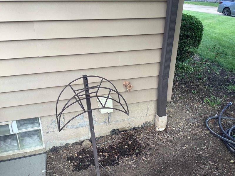 Responded to water leak complaint following previous repair work on exterior spigot. Upon inspection, discovered that activating the outdoor faucet caused water intrusion through interior ceiling, indicating a compromised supply line or connection point between the exterior hose bib and interior plumbing system. Documented exterior spigot location on concrete patio area near drainage system and foundation perimeter where leak originated. Further investigation required to access concealed piping within wall cavity to identify exact failure point and complete permanent repair of water supply line.
