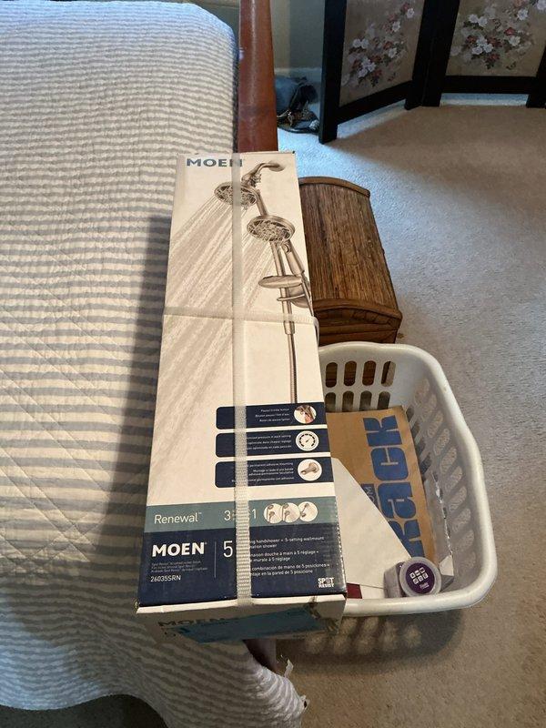Installed customer-supplied Moen Renewal handheld shower head assembly with wall bracket and flexible metal hose in bathroom shower/tub area. Verified proper mounting, connection integrity, and functionality of the new fixture upon completion.