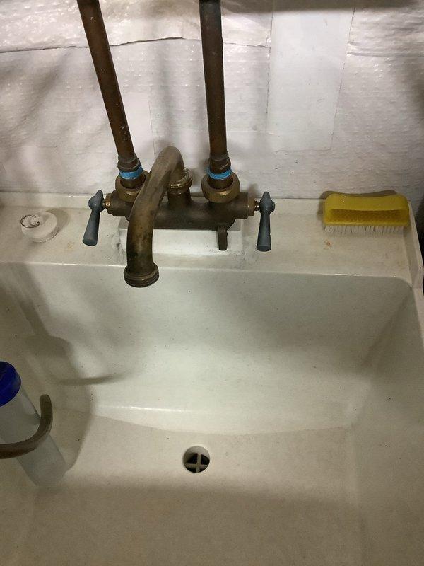 Responded to service call for leaking valve and brass faucet at utility sink. Upon inspection, identified failed plastic trap assembly and leaking brass faucet with worn internal components. Replaced plastic trap with new assembly, ensuring proper alignment and seal. Repaired brass faucet by replacing worn washers and seals on manifold valves with black handles. Tested all connections for leaks, verified proper water flow through both hot and cold supply lines, and confirmed shut-off valves operate correctly. All plumbing fixtures now functioning properly with no active leaks detected.
