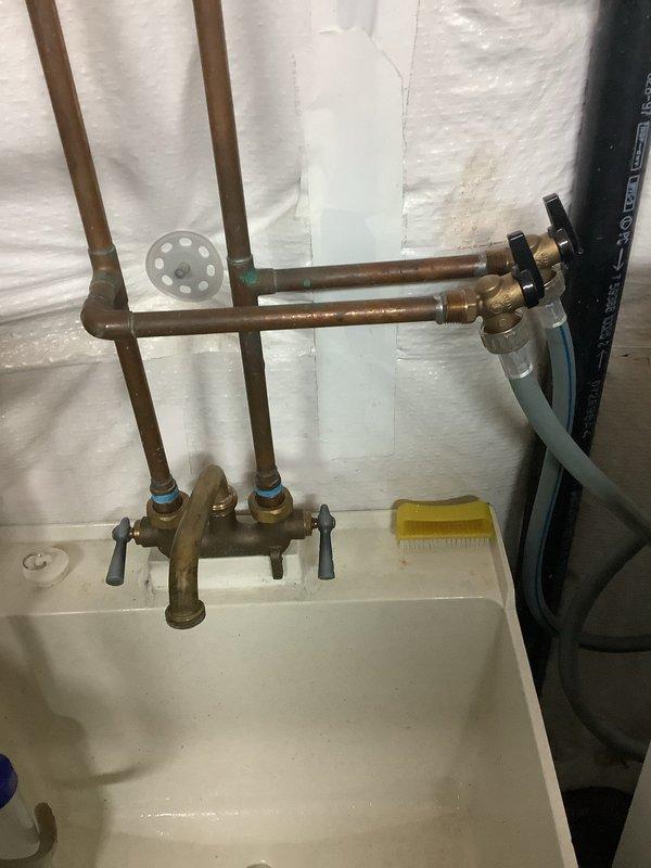 Responded to service call for leaking valve and brass faucet at utility sink. Upon inspection, identified failed plastic trap assembly and leaking brass faucet with worn internal components. Replaced plastic trap with new assembly, ensuring proper alignment and seal. Repaired brass faucet by replacing worn washers and seals on manifold valves with black handles. Tested all connections for leaks, verified proper water flow through both hot and cold supply lines, and confirmed shut-off valves operate correctly. All plumbing fixtures now functioning properly with no active leaks detected.