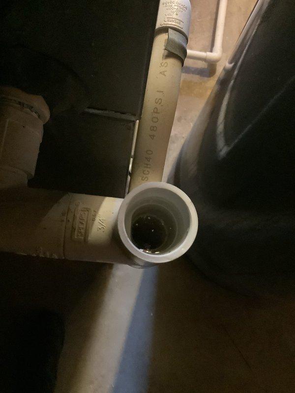 Responded to service call for water draining onto floor instead of through drain pipe. Upon inspection, found standing water in PVC condensate drain line and extensive water pooling on basement floor around HVAC unit. Identified drainage issue with condensate system causing water to overflow onto concrete surface rather than properly evacuating through drain piping. Documented conditions showing water accumulation in drain line and moisture damage on floor surrounding equipment.