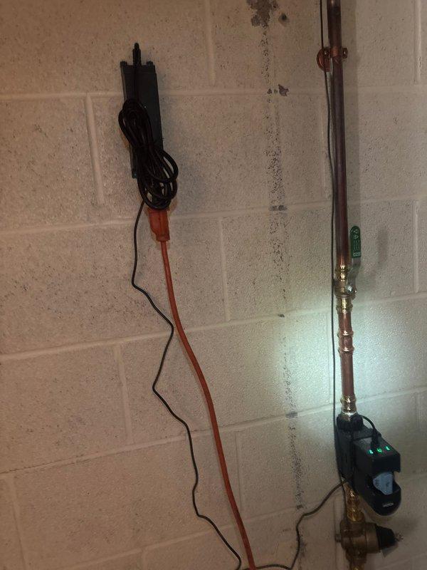 Completed installation of basic plumbing circuit protection system in basement utility area. Installed water sensor device with LED indicator on copper supply line near water heater, mounted electrical monitoring equipment to floor joists in crawl space with proper wiring routing through insulation, and ran new electrical circuits along concrete block wall to support plumbing safety monitoring system.