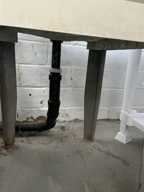 Completed installation of customer-supplied sink with new stainless steel fixture and pull-down faucet in kitchen area. Ran supply lines and drain connections for new dishwasher installation, including PVC drainage system with proper mounting brackets secured to basement wall structure. Cleared existing drain blockages to ensure proper flow and tested all connections for leaks. All plumbing components installed to code with white PVC drainage visible in crawl space area beneath kitchen, properly supported and vented for optimal performance.