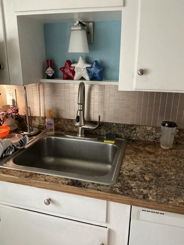 Completed installation of customer-supplied sink with new stainless steel fixture and pull-down faucet in kitchen area. Ran supply lines and drain connections for new dishwasher installation, including PVC drainage system with proper mounting brackets secured to basement wall structure. Cleared existing drain blockages to ensure proper flow and tested all connections for leaks. All plumbing components installed to code with white PVC drainage visible in crawl space area beneath kitchen, properly supported and vented for optimal performance.