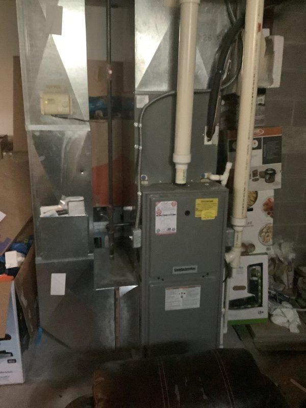 Completed estimate for replacement of 26-year-old HVAC system with identified refrigerant leak. Inspected existing gray furnace unit with Aprilaire humidistat control, associated ductwork, and condensate drainage system in basement utility area. Documented current equipment configuration including electrical connections, copper refrigerant lines with service valves, PVC venting, and mechanical components for replacement quote preparation and customer approval.