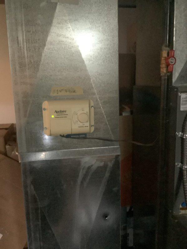 Completed estimate for replacement of 26-year-old HVAC system with identified refrigerant leak. Inspected existing gray furnace unit with Aprilaire humidistat control, associated ductwork, and condensate drainage system in basement utility area. Documented current equipment configuration including electrical connections, copper refrigerant lines with service valves, PVC venting, and mechanical components for replacement quote preparation and customer approval.