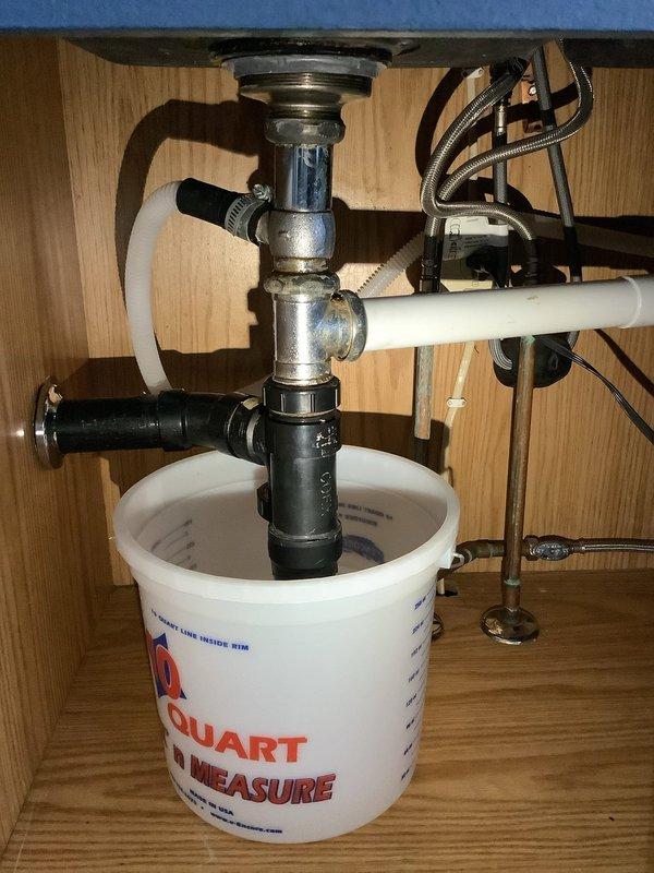Responded to service call for active leak under kitchen sink. Upon inspection, identified leak originating from garbage disposal drain connections and sink tailpiece assembly. Tightened disposal mounting flange, discharge elbow connection, and dishwasher inlet port. Inspected PVC drain lines and P-trap connections for proper sealing. Verified water supply line connections to shutoff valves were secure with no signs of leakage. Tested system by running water through sink and operating garbage disposal unit to confirm all connections were watertight and leak was resolved.