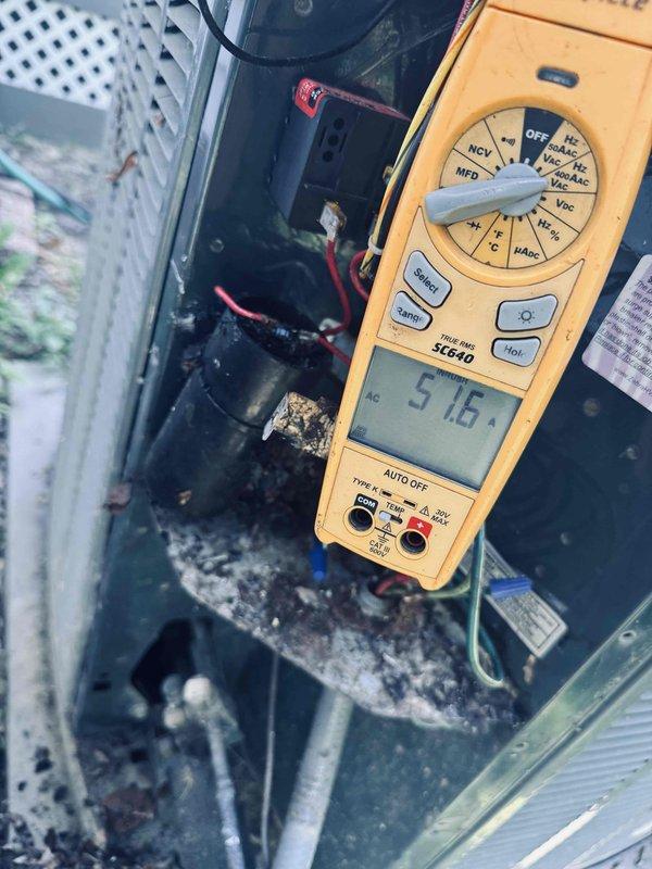 Responded to no cooling complaint on 13-year-old air conditioning system. Upon inspection, found outdoor condensing unit with significant debris accumulation in cabinet affecting airflow and component operation. Performed voltage diagnostics using multimeter, recording 515.7 volts during testing to assess electrical system functionality. Removed access panel and inspected internal components including capacitor and wiring connections. Cleaned debris consisting of leaves, dirt, and organic matter from unit interior to restore proper airflow and prevent future component damage. Verified all electrical connections were secure and capacitor was functioning within specifications. System restored to normal cooling operation.