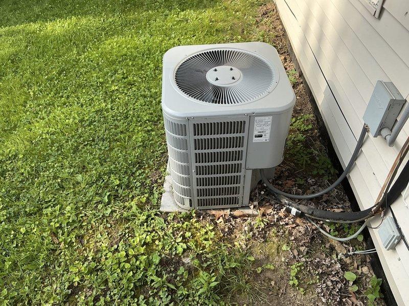 Completed comprehensive HVAC system replacement estimate for residential property referred by existing customers. Assessed existing Whirlpool furnace system installed in interior utility closet and outdoor air conditioning condenser unit mounted on concrete pad adjacent to vinyl-sided exterior wall. Documented current system configuration including vertical furnace installation with overhead ductwork, copper refrigerant line routing, and outdoor condenser with disconnect box and refrigerant lines secured to building exterior.