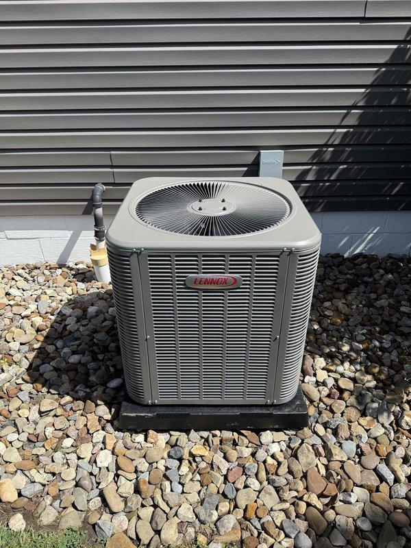 Completed installation of new Lennox air conditioning system with matching evaporator coil at residential property. Positioned outdoor condensing unit on level gravel bed with proper clearance for airflow and service access, mounted on vibration-dampening pad. Installed refrigerant line set with appropriate insulation, connected service valves with brass fittings, and pressure-tested system for leaks. Verified proper drainage, electrical connections, and system startup. Unit is operational and cooling efficiently.