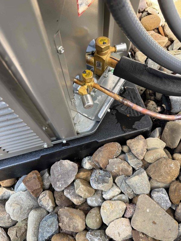 Completed installation of new Lennox air conditioning system with matching evaporator coil at residential property. Positioned outdoor condensing unit on level gravel bed with proper clearance for airflow and service access, mounted on vibration-dampening pad. Installed refrigerant line set with appropriate insulation, connected service valves with brass fittings, and pressure-tested system for leaks. Verified proper drainage, electrical connections, and system startup. Unit is operational and cooling efficiently.