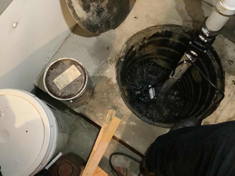 Responded to active water leak in basement of 18-year-old home where water was coming up through the floor. Upon arrival, inspected sump pump system and identified failure in the existing sump pump assembly. Removed compromised pump unit and associated components from the basin. Cleaned debris and sediment from the sump pit to ensure proper operation. Installed replacement submersible sump pump with new discharge piping and check valve. Verified proper pump operation and drainage function. Tested system under load to confirm water was being effectively removed from the pit and discharged away from the foundation. All plumbing connections secured and system restored to full working order, eliminating the active leak condition.