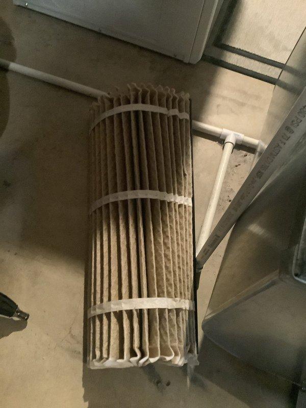 Responded to no-cooling complaint on 10-year-old residential air conditioning system. Upon arrival, found outdoor condensing unit heavily soiled with dirt, dust, and debris accumulation on exterior surfaces and coil areas. Performed diagnostic testing with manifold gauges to assess system pressures and operational status. Inspected indoor air handler and discovered severely clogged cylindrical pleated air filter with significant dust and particulate buildup restricting airflow. Replaced dirty filter with new unit to restore proper system airflow and efficiency. Cleaned condensing unit exterior and coil surfaces to improve heat transfer capability. System restored to normal cooling operation.